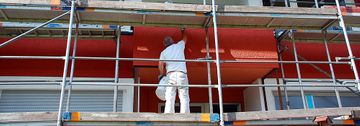 Holzwarth GmbH in Ubstadt-Weiher, Maler auf Gerüst streicht die Außenfassade eines Mehrfamilienhauses