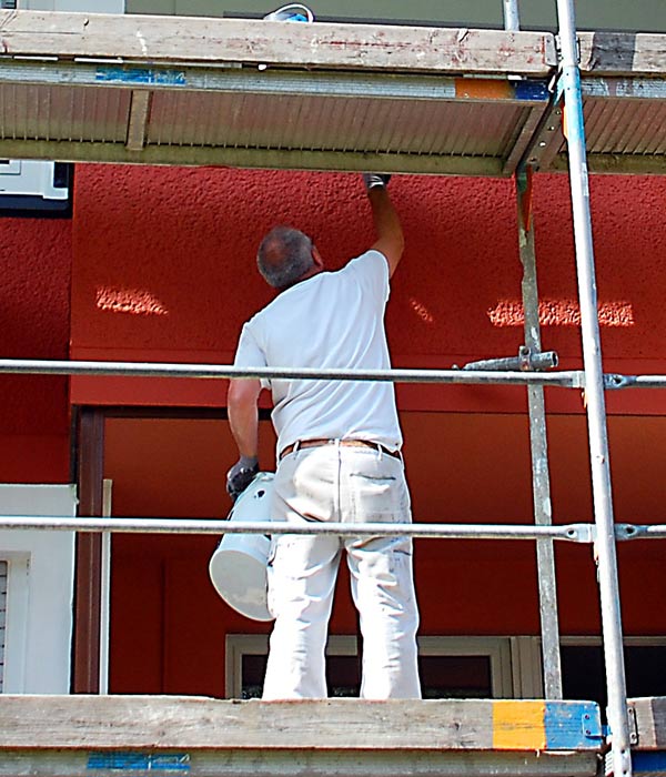 Holzwarth GmbH in Ubstadt-Weiher, Maler auf Gerüst streicht die Außenfassade eines Mehrfamilienhauses